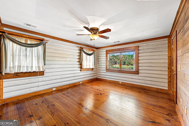 unfurnished room with ceiling fan, hardwood / wood-style floors, and log walls