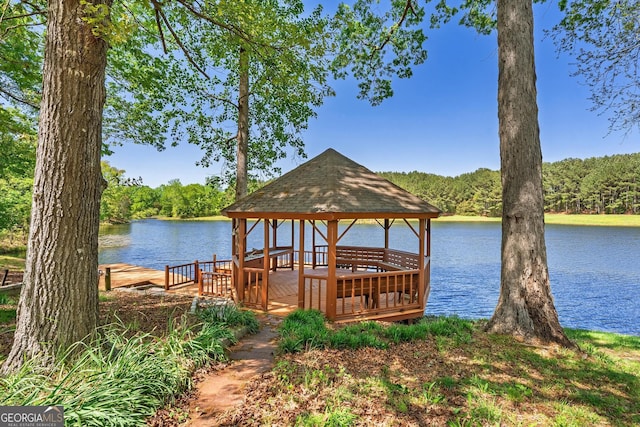 view of dock featuring a gazebo, a wooded view, and a water view