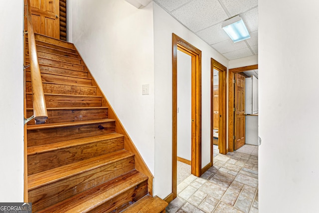 stairway featuring a drop ceiling