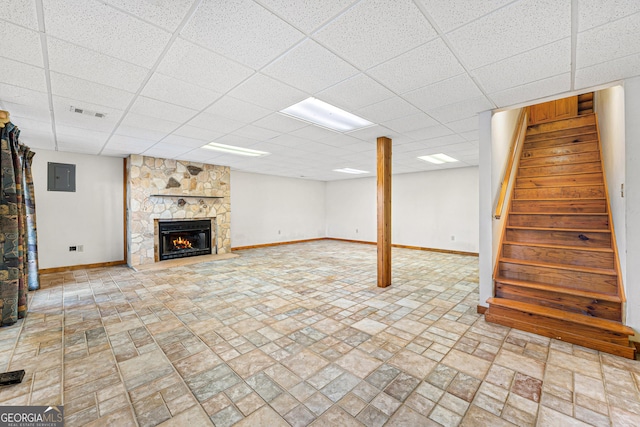 basement with a fireplace, electric panel, and a drop ceiling