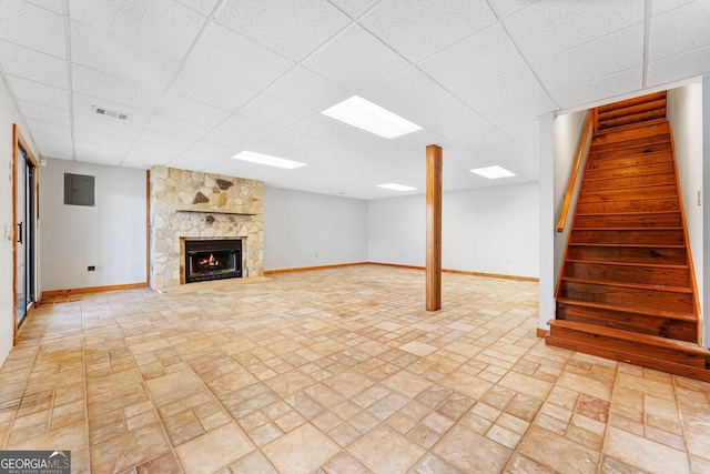 finished below grade area with baseboards, brick patterned floor, stairs, and a drop ceiling