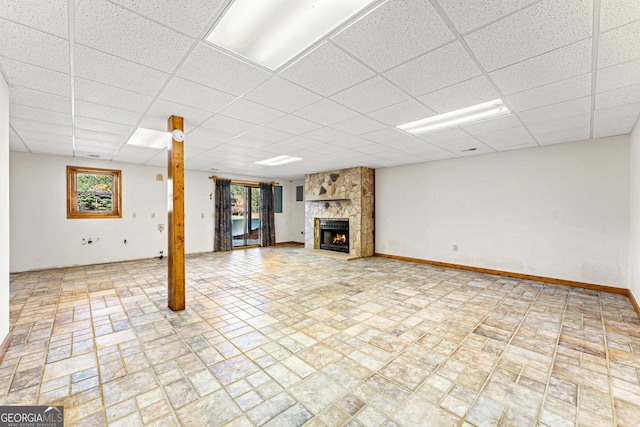 basement with a stone fireplace and a paneled ceiling