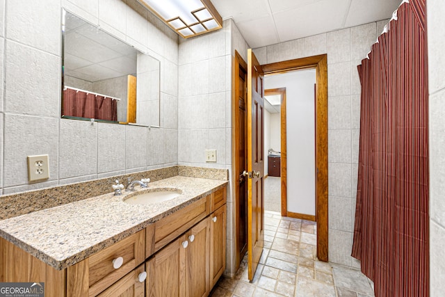 bathroom featuring vanity and tile walls