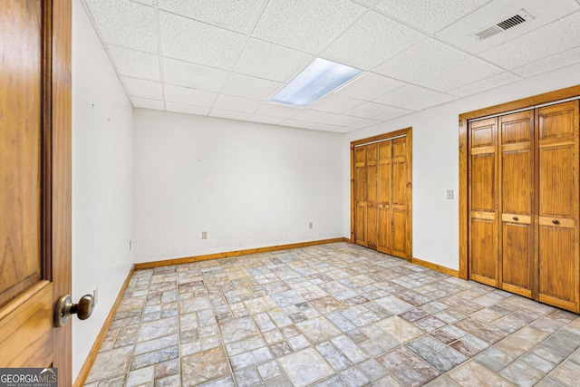 unfurnished bedroom featuring baseboards, a paneled ceiling, and visible vents