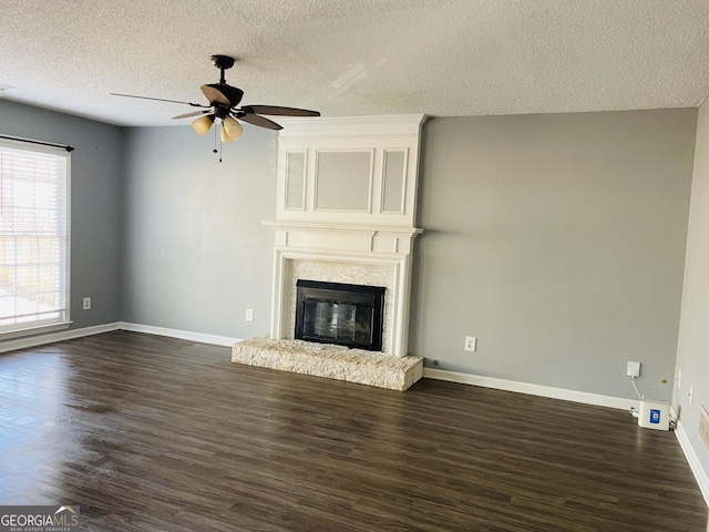 unfurnished living room featuring a textured ceiling, dark wood-type flooring, a large fireplace, and ceiling fan