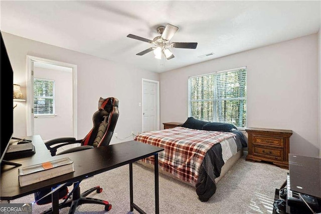 bedroom featuring multiple windows, ceiling fan, and light carpet