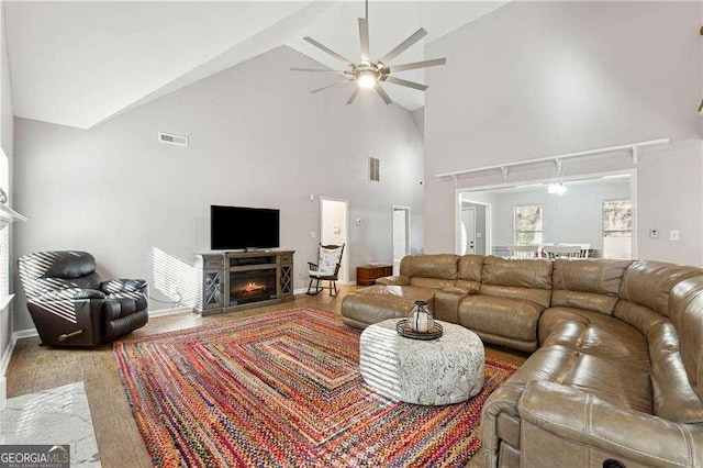 living room featuring wood-type flooring, high vaulted ceiling, and ceiling fan