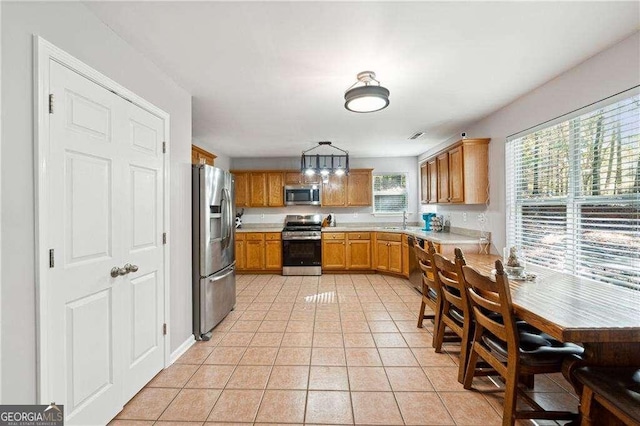 kitchen featuring light tile patterned flooring, stainless steel appliances, hanging light fixtures, and sink