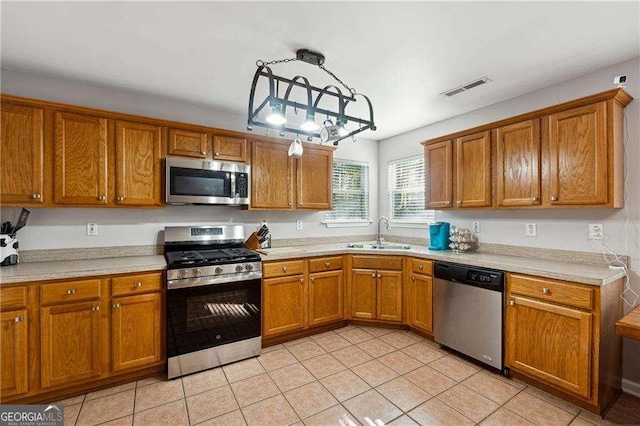 kitchen featuring light tile patterned flooring, pendant lighting, stainless steel appliances, and sink