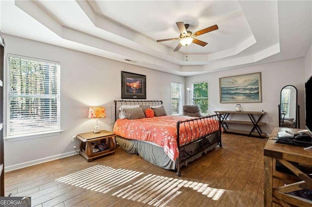 bedroom featuring a raised ceiling, ceiling fan, and hardwood / wood-style floors