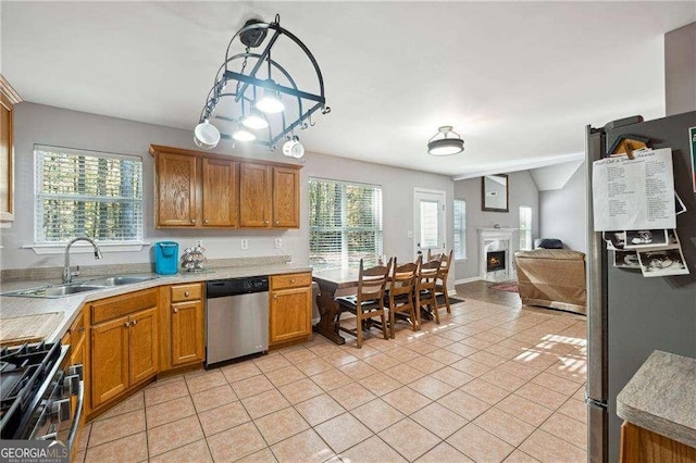 kitchen with sink, light tile patterned floors, stainless steel appliances, and hanging light fixtures