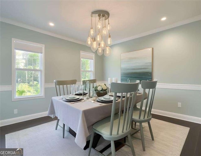 dining space with hardwood / wood-style floors, ornamental molding, and an inviting chandelier