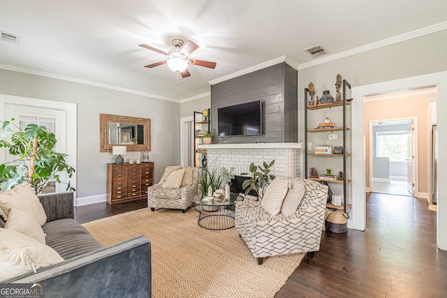 living room with dark hardwood / wood-style floors, ceiling fan, ornamental molding, and a brick fireplace