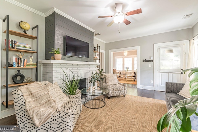 living room with a fireplace, ceiling fan, ornamental molding, and dark wood-type flooring