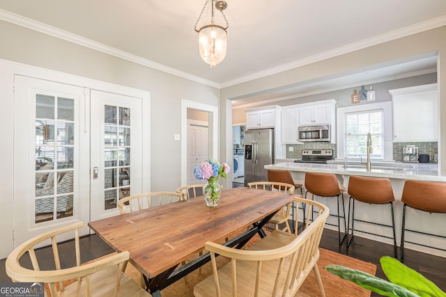 dining area featuring crown molding, sink, and dark wood-type flooring