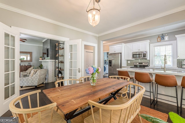 dining room featuring sink, ornamental molding, dark wood-type flooring, and french doors