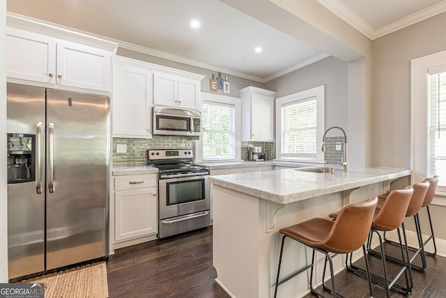 kitchen featuring a center island with sink, sink, dark hardwood / wood-style floors, appliances with stainless steel finishes, and white cabinetry