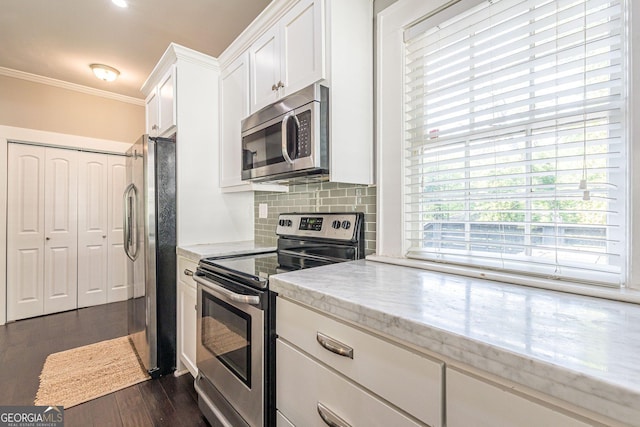 kitchen with white cabinetry, dark wood-type flooring, stainless steel appliances, light stone counters, and crown molding