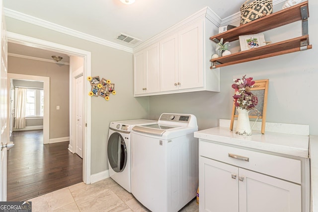 laundry room featuring cabinets, light wood-type flooring, crown molding, and separate washer and dryer