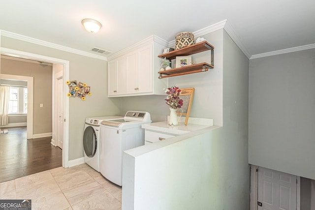 clothes washing area with washer and dryer, cabinets, crown molding, and light hardwood / wood-style flooring