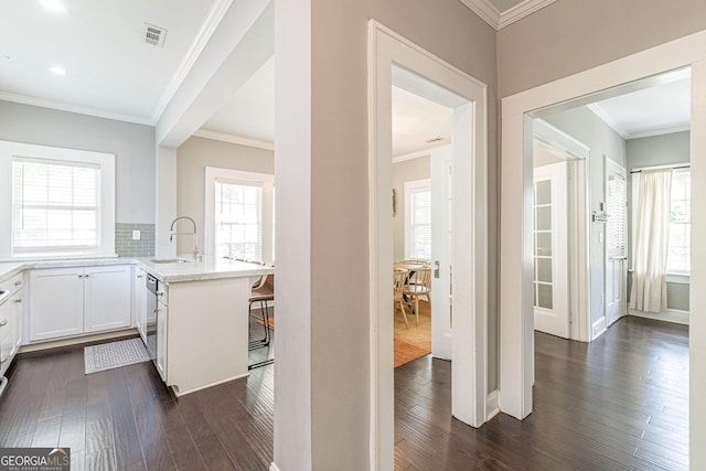 kitchen featuring sink, dark hardwood / wood-style flooring, kitchen peninsula, a breakfast bar, and white cabinets