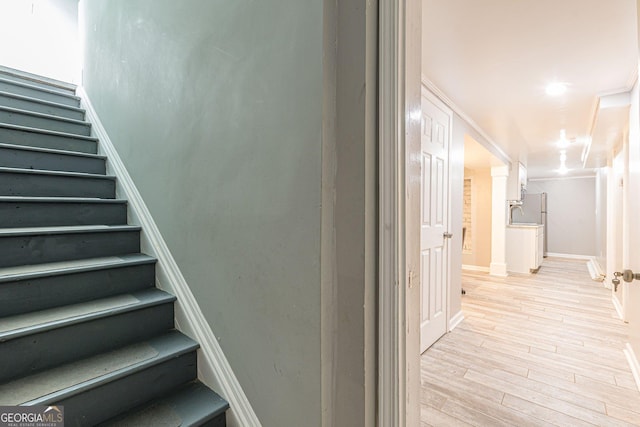 stairs with crown molding and hardwood / wood-style flooring