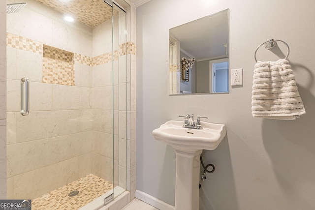 bathroom with sink, a shower with shower door, and crown molding