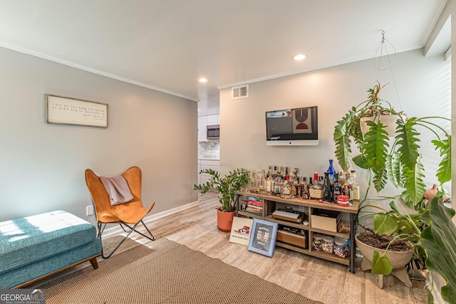 living room with ornamental molding, indoor bar, and light wood-type flooring