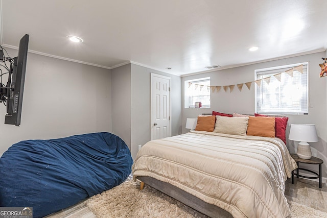 bedroom with hardwood / wood-style flooring, ornamental molding, and multiple windows