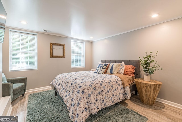 bedroom with multiple windows, crown molding, and light hardwood / wood-style floors