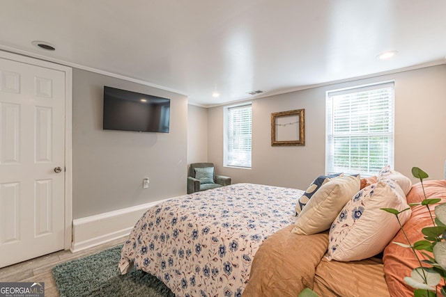 bedroom featuring multiple windows, crown molding, and wood-type flooring