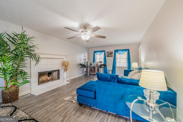 living room with ceiling fan, a fireplace, and wood-type flooring