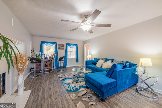 living room with a textured ceiling, light wood-type flooring, and ceiling fan