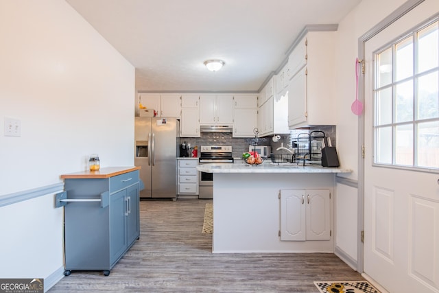 kitchen with kitchen peninsula, appliances with stainless steel finishes, light hardwood / wood-style floors, and white cabinetry