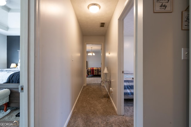 hallway featuring a textured ceiling and light carpet