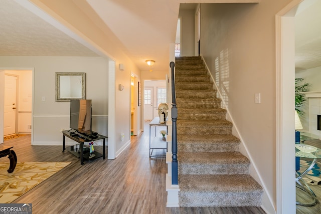 stairway with wood-type flooring and a tiled fireplace