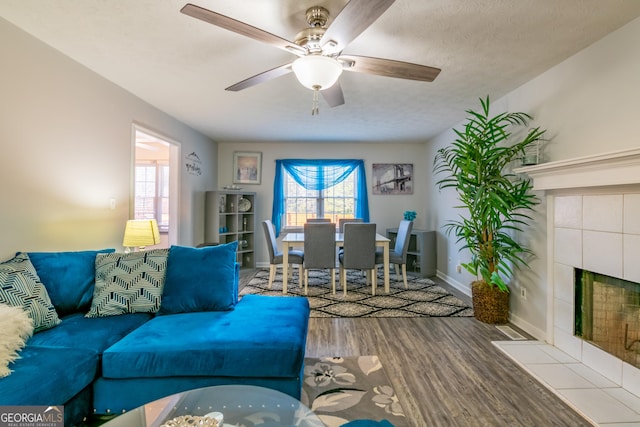 living room featuring a fireplace, ceiling fan, hardwood / wood-style floors, and a textured ceiling