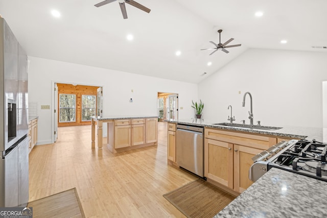 kitchen with light stone countertops, light brown cabinetry, stainless steel appliances, sink, and light hardwood / wood-style floors