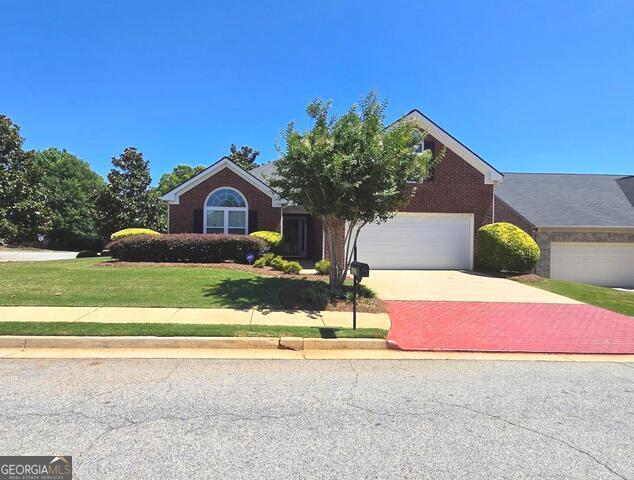 view of front of home with a garage, a front yard, decorative driveway, and brick siding