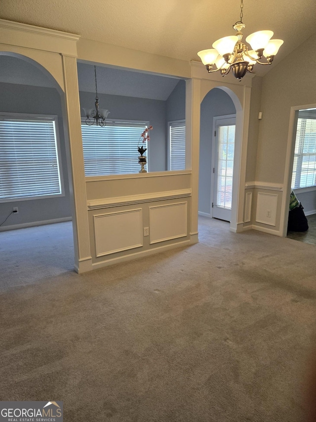 interior space featuring a chandelier, arched walkways, lofted ceiling, and a decorative wall