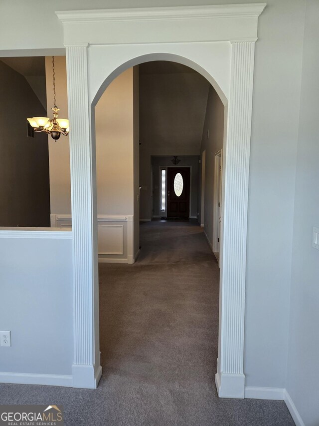 unfurnished dining area with carpet flooring, an inviting chandelier, and vaulted ceiling