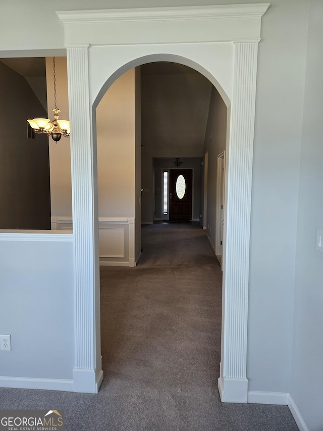 corridor with arched walkways, carpet flooring, lofted ceiling, and an inviting chandelier