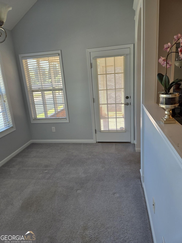 doorway featuring carpet, lofted ceiling, and baseboards