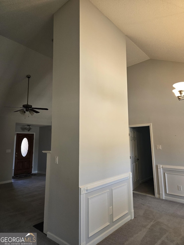 corridor featuring a wainscoted wall, high vaulted ceiling, carpet flooring, and a decorative wall