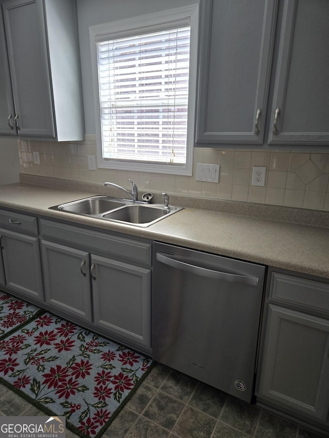 kitchen with light countertops, stainless steel dishwasher, backsplash, and a sink