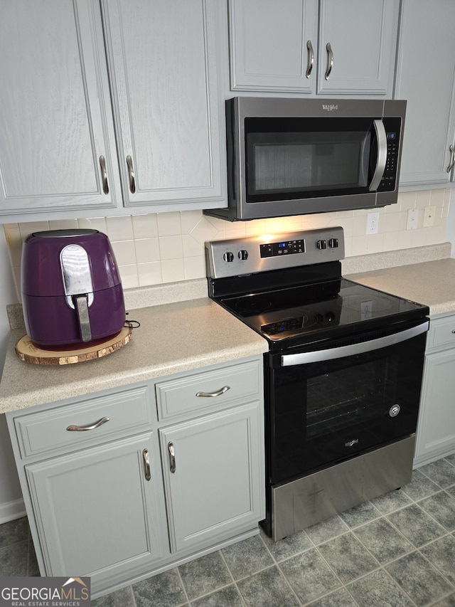 kitchen with appliances with stainless steel finishes, white cabinets, light countertops, and decorative backsplash