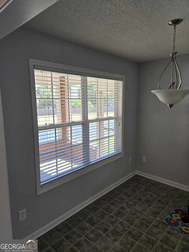 unfurnished dining area featuring baseboards and a textured ceiling