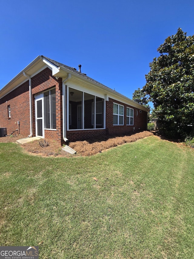 view of property exterior featuring a yard, a sunroom, and brick siding