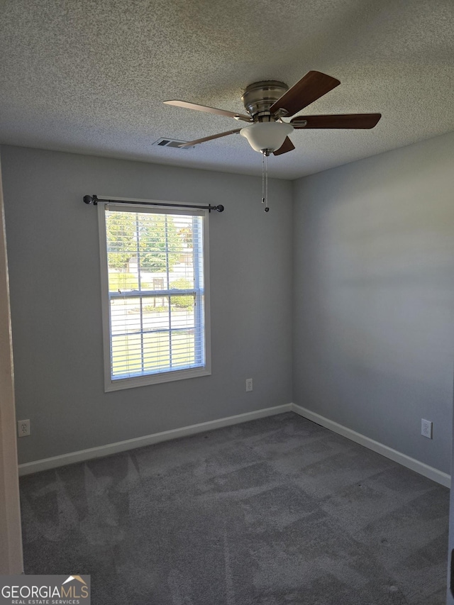 empty room featuring a textured ceiling, dark carpet, and baseboards