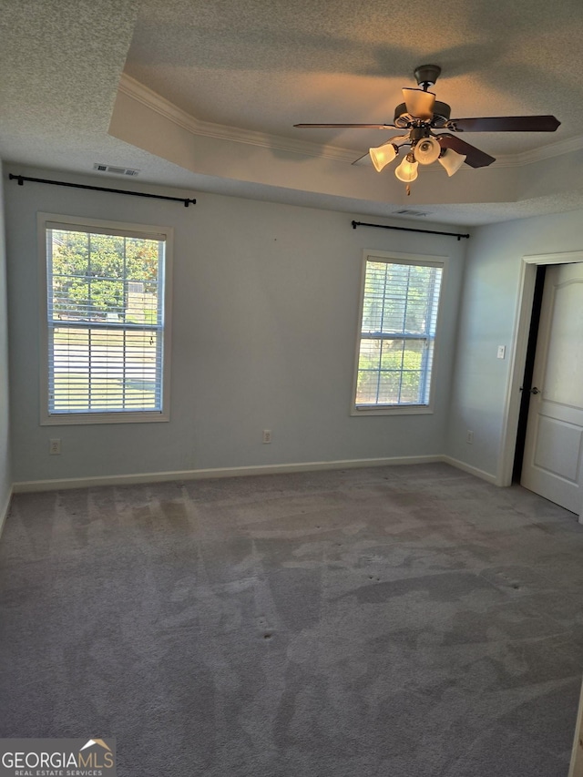 unfurnished room with visible vents, a raised ceiling, a textured ceiling, and ornamental molding